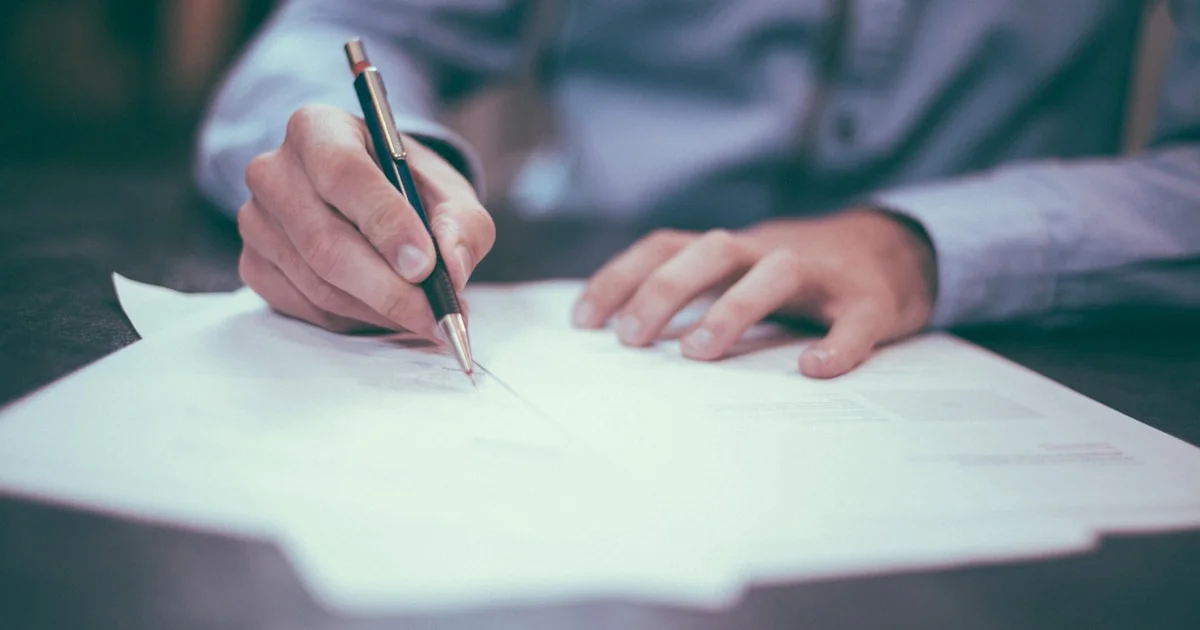 Person signing business documents at a desk